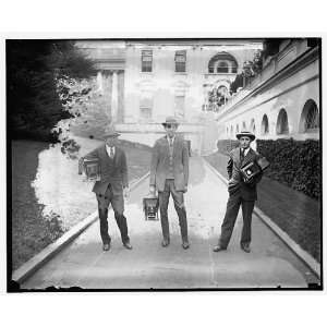   Man in suit carrying equipment cases in stadium 1909