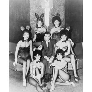 1962 photo Hugh Hefner, full length portrait, seated surrounded by 